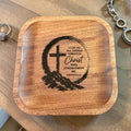 A square wooden tray with rounded corners, featuring a laser-engraved Christian cross and Bible verse on the lid, displayed on a wooden tabletop 